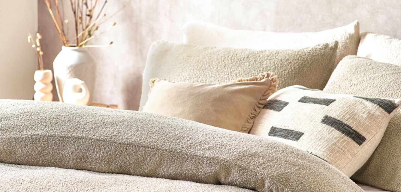 Cream colour drenched bedroom featuring cream boucle bedding, cream throw cushions and a cream wall