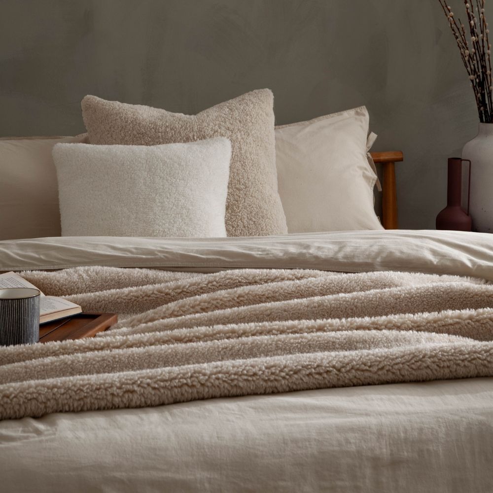 Cream colour drenched bedroom with a beige fleece throw, beige duvet and fleece cushions