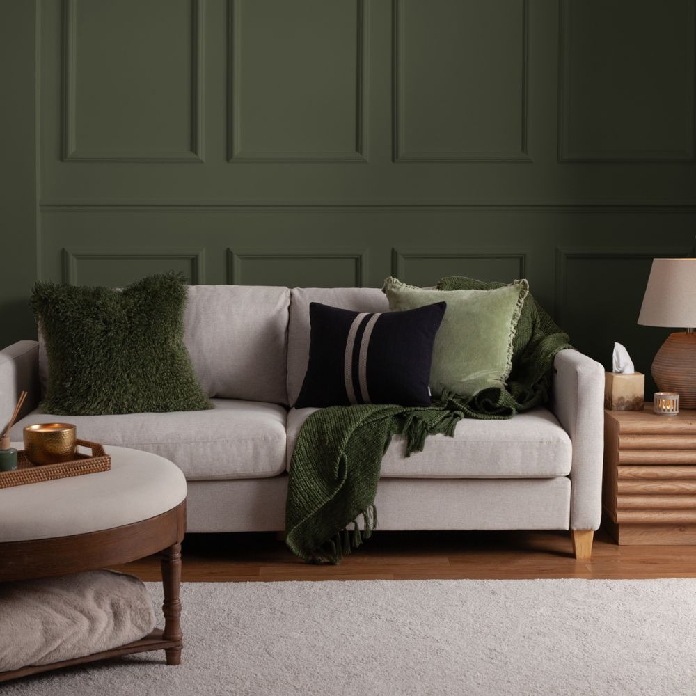 green colour drenched living room, cream sofa with green cushions in front of a green wall.