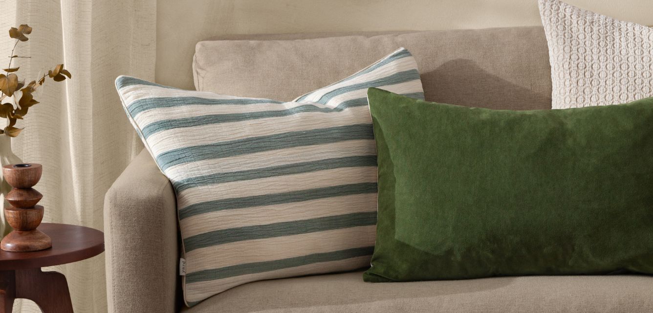 beige sofa, with stripey navy and white cushion, green cushion and cream cushion, emphasising slow decorating