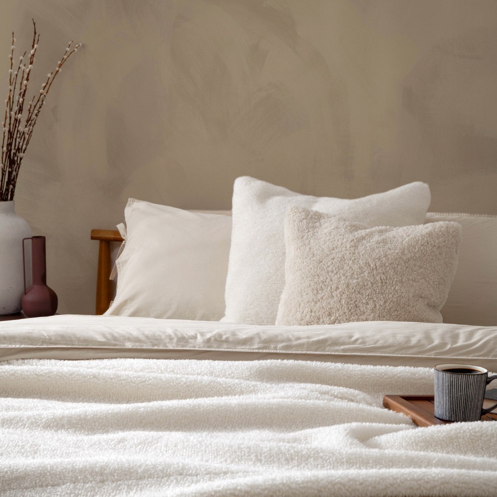 Beige bedroom, with sherpa fleece throw and cushions, clearly intentionally styled