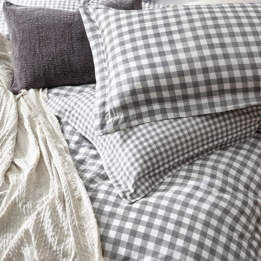checkered grey bedding with a grey cushion and a white throw.