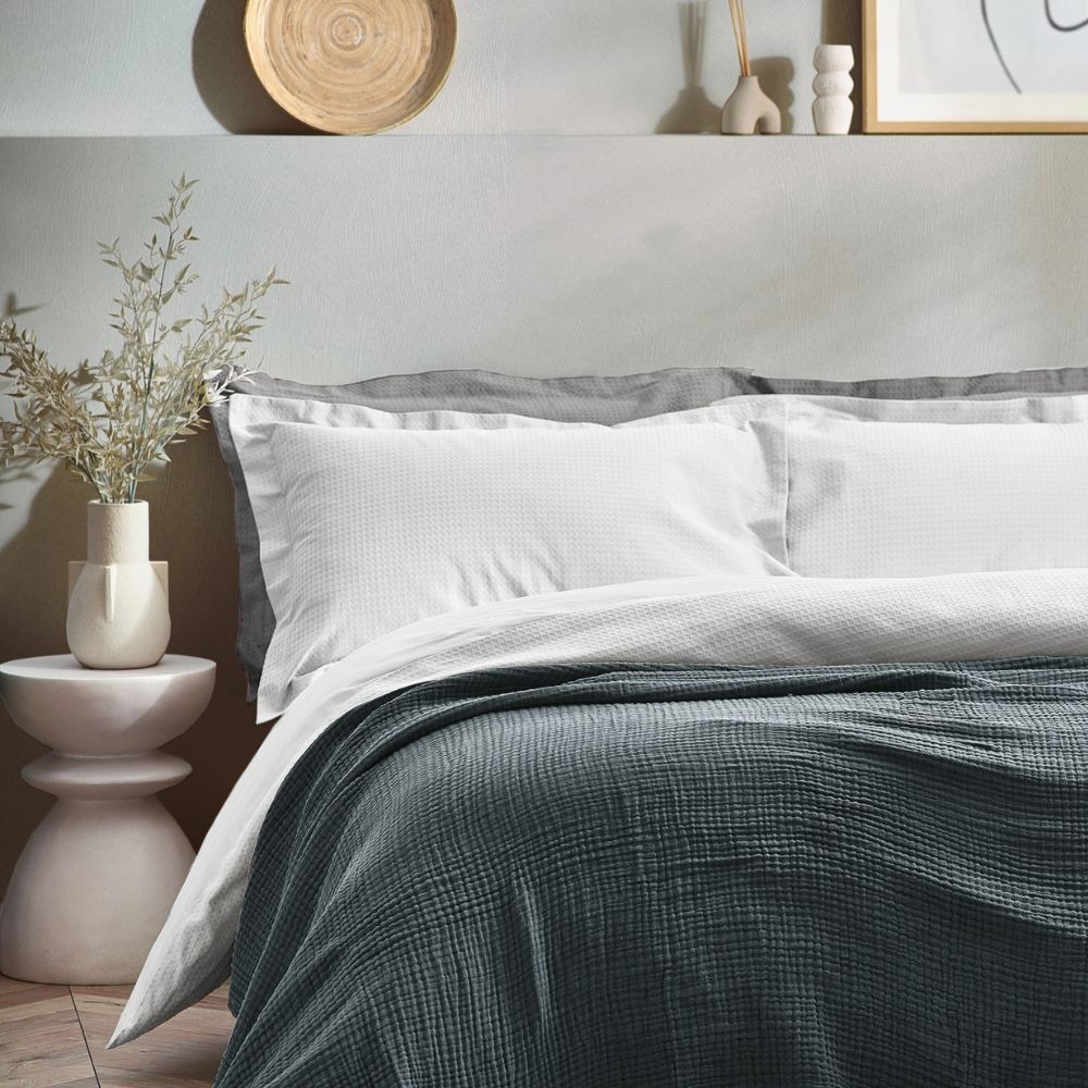 white and grey bedding with a blue throw blanket paired well with grey.