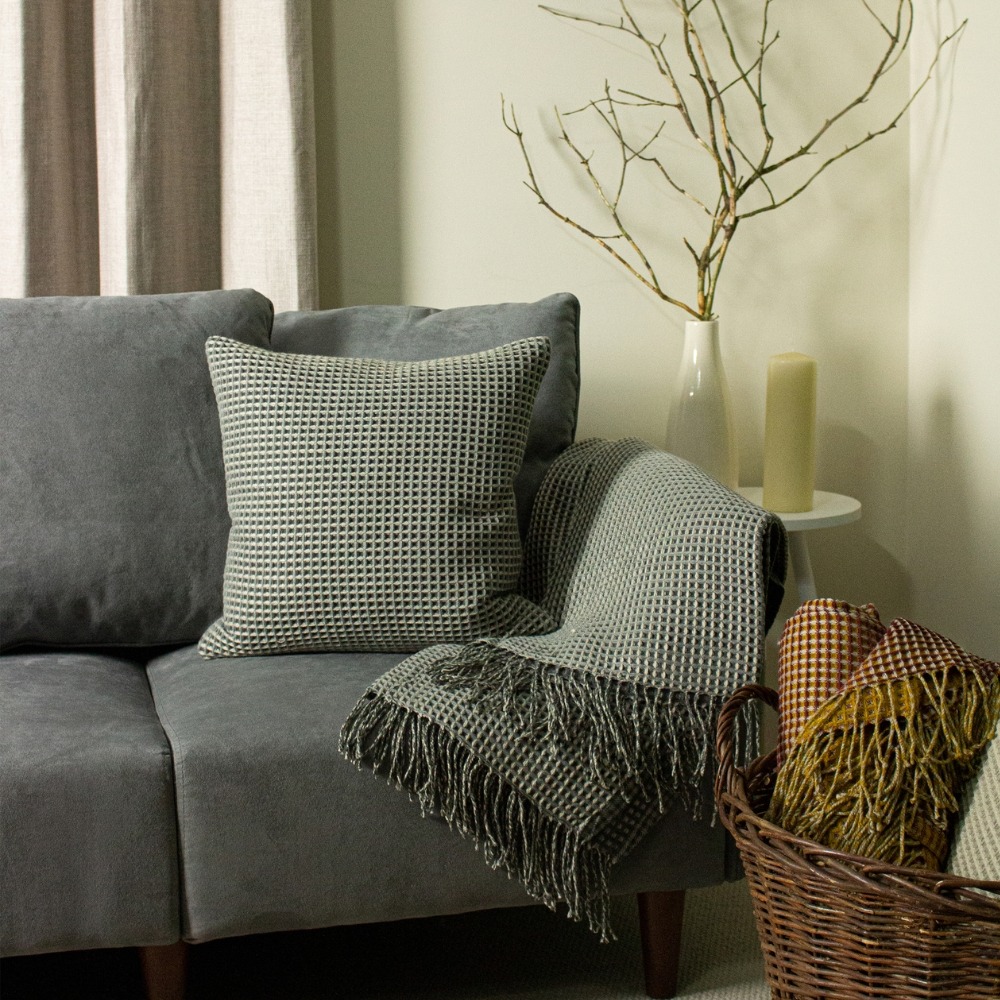 dark grey sofa with a grey cushion and a grey throw.