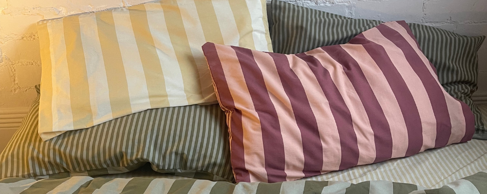 A green stripped bedding set, with pillowcases in matching striped patterns, but one in yellow and the other in pink