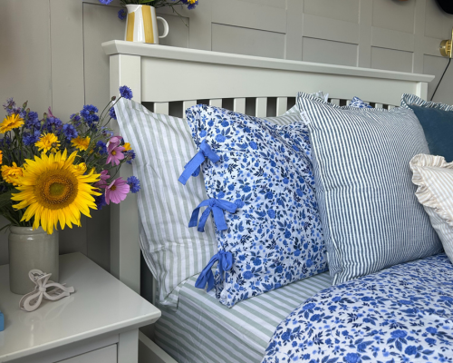 A blue floral bed set, with blue striped bed sheets, blue striped pillowcases and blue cushions
