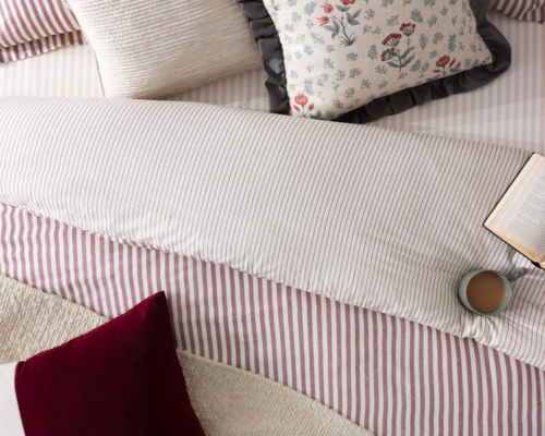 Ared coloured stripe duvet cover that's reversible with a narrow stripe, with floral cushions and a dark red velvet cushion on the top