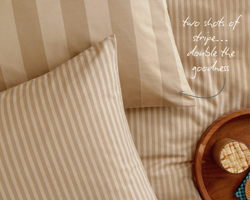 A neutral coloured striped duvet cover, with matching striped pillow cases on top