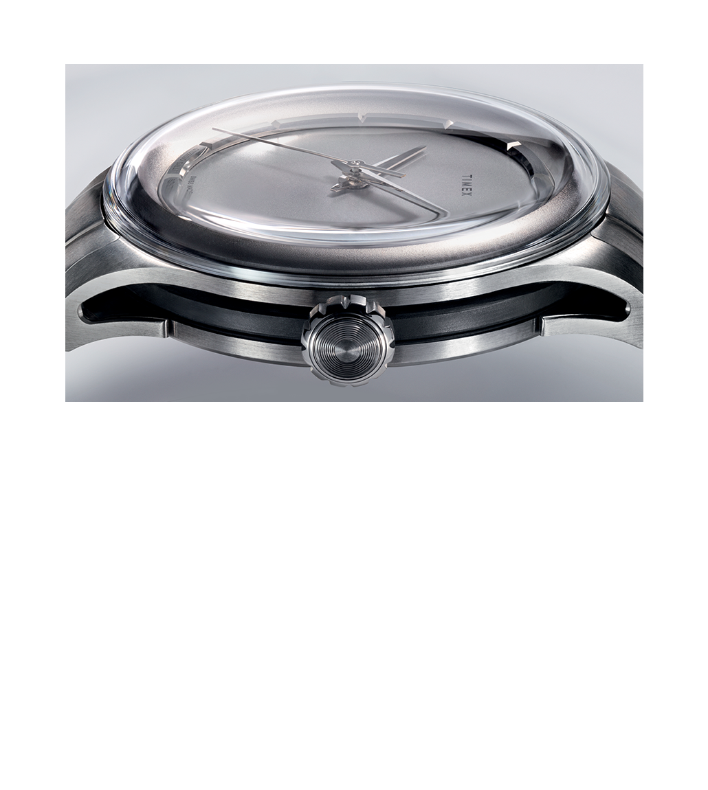 A side-angle view of the watch showcasing its curved sapphire crystal, the brushed titanium case, and the unique cutout design of the lugs. The crown is visible with its intricate ridged texture.