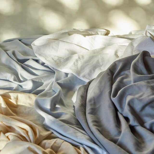 The evening sunlight shining on the Slumber Cloud Essential Sheet Set in various colors