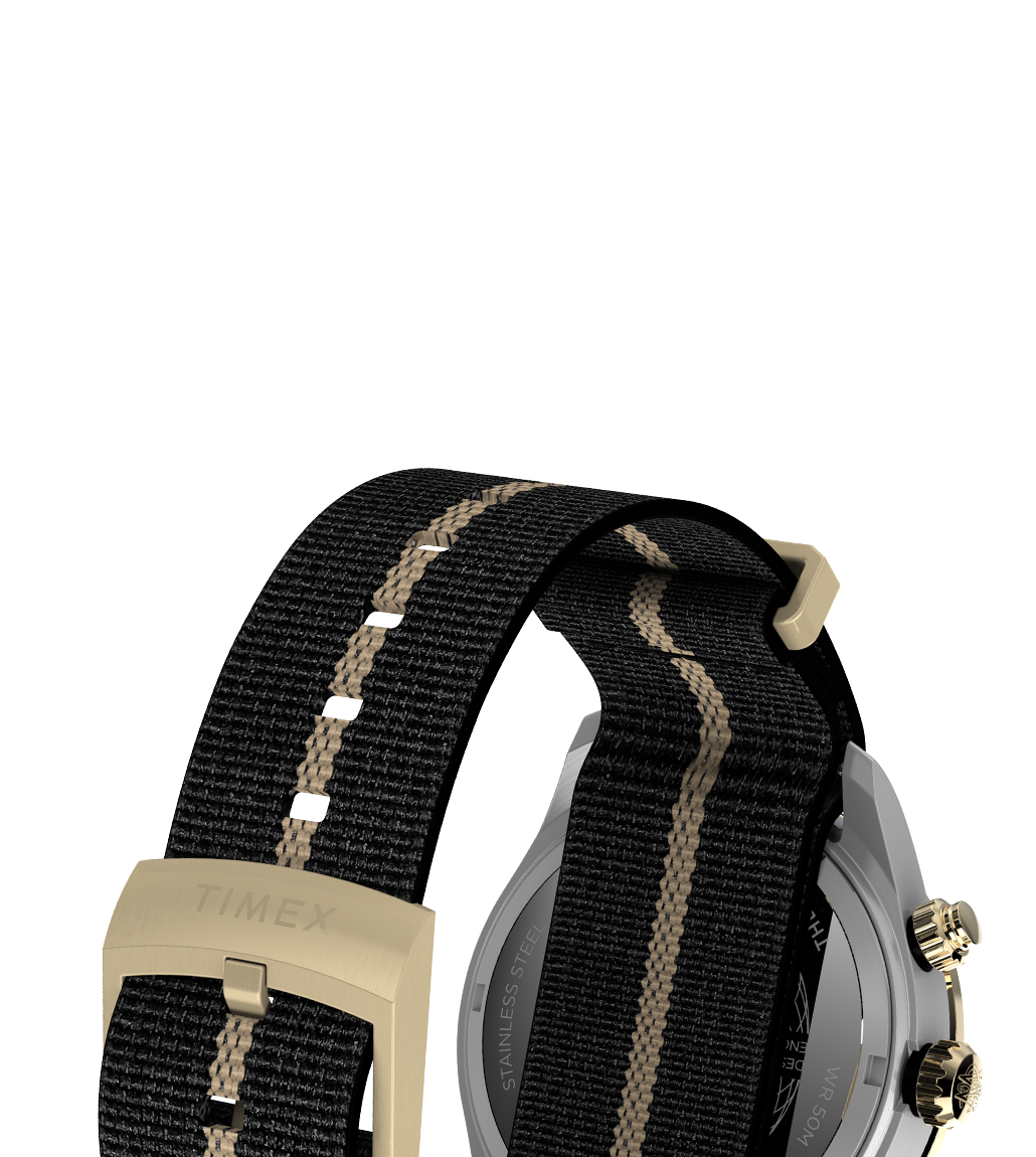 Detail image of the Timex Waterbury Heritage Chronograph’s black fabric strap with a central tan stripe, gold-tone buckle engraved with “TIMEX”, and stainless steel case back partially visible.