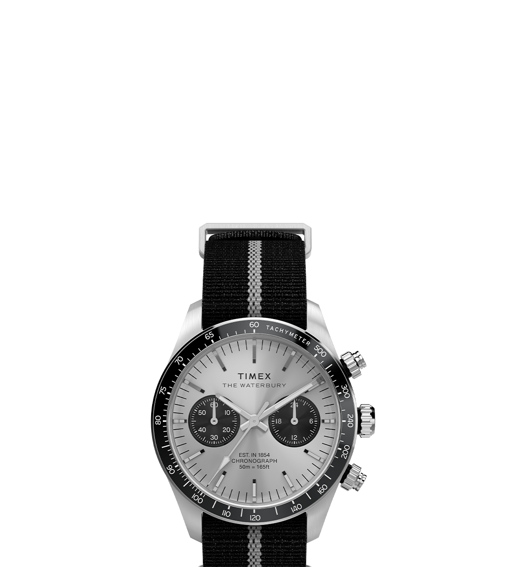 Front product image of the Timex Waterbury Heritage Chronograph featuring a brushed silver-tone dial with black sub-dials, black tachymeter bezel, silver-tone hands and markers, and a black strap with a white central stripe and silver hardware.