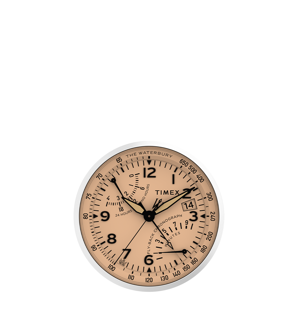 Zoomed-in frontal view focusing on the intricate dial of the Waterbury Traditional Fly-back Chronograph. The peach-salmon colored face is detailed with aviation-style sub-dials, crisp black numerals, and a fly-back minutes counter. The chronograph seconds and sub-dial hands are clearly visible, along with the date display.