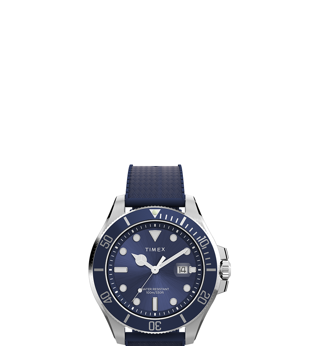 A product shot of the Timex Harborside Coast watch against a white background. The watch features a navy blue dial and strap, luminous markers, and silver-toned hands, with a unidirectional rotating bezel and 100m water resistance marking on the dial.