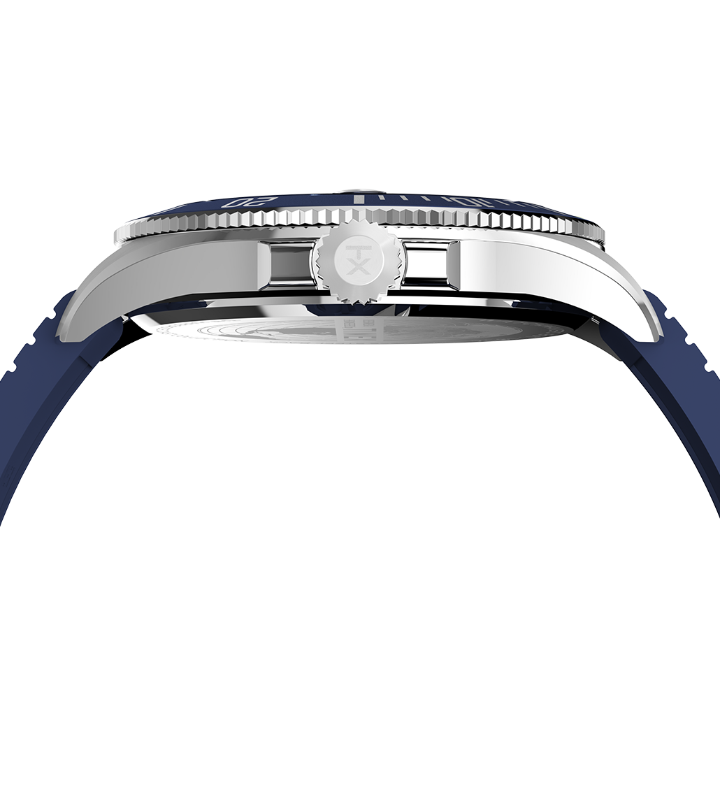 Side profile of the Timex Harborside Coast watch showing its stainless steel case and blue silicone strap. The crown bears the Timex “TX” logo, and the slightly domed crystal and bezel detail are visible from this angle.