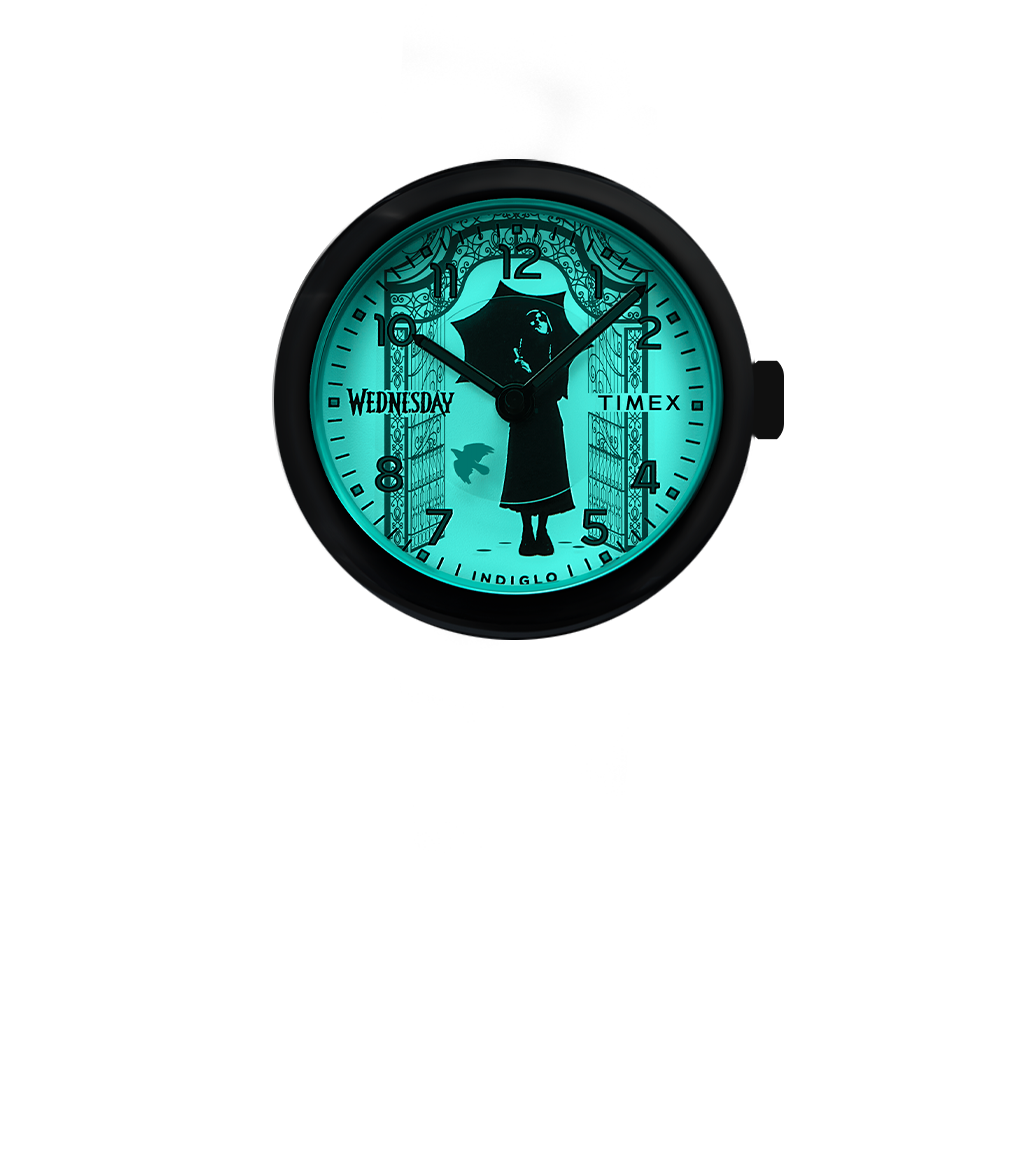 Timex x Wednesday analog watch with the Indiglo backlight activated, revealing hidden gothic gate artwork and added details illuminating the silhouette of Wednesday.