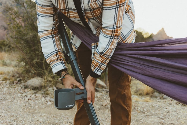 Man attaching Swiftlet Cup Holder to the arm of the Swiftlet portable hammock stand.