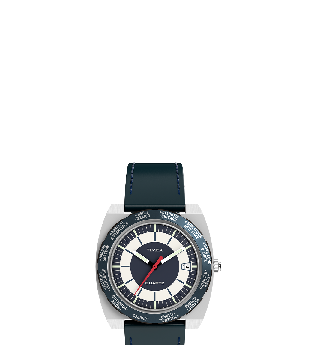 Front view of the Q Timex® 1972 World Time watch featuring a navy blue leather strap with blue stitching, a stainless-steel cushion case, and a world time bezel marked with major global cities. The dial is split into cream and navy sections with minimal hour markers, a red seconds hand, and a date window at 3 o’clock.
