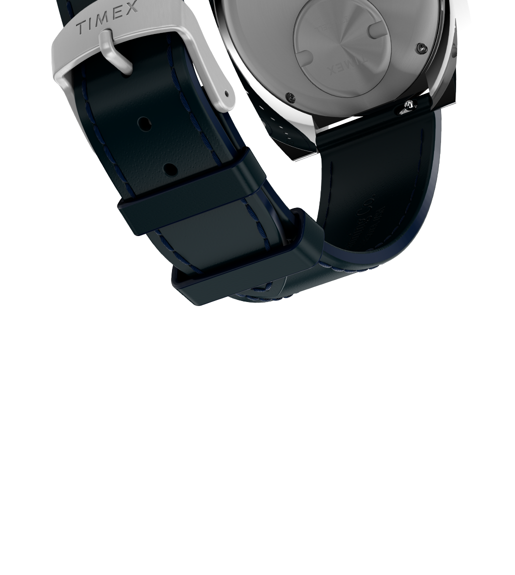 Rear view of the Q Timex® 1972 World Time watch showing the engraved stainless-steel case back and the navy leather strap with dark blue stitching and a polished buckle engraved with the “TIMEX” logo.