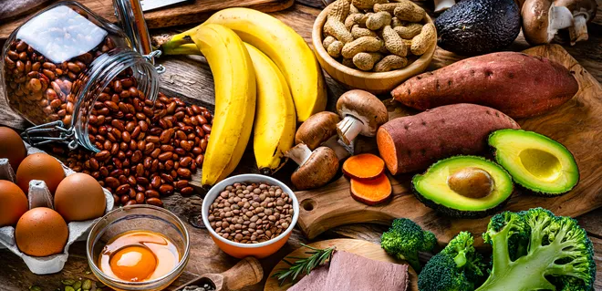 Variety of foods containing biotin, Vitamin C, and Vitamin A, including eggs, bananas, peanuts, sweet potatoes, avocados, mushrooms, broccoli, and lentils