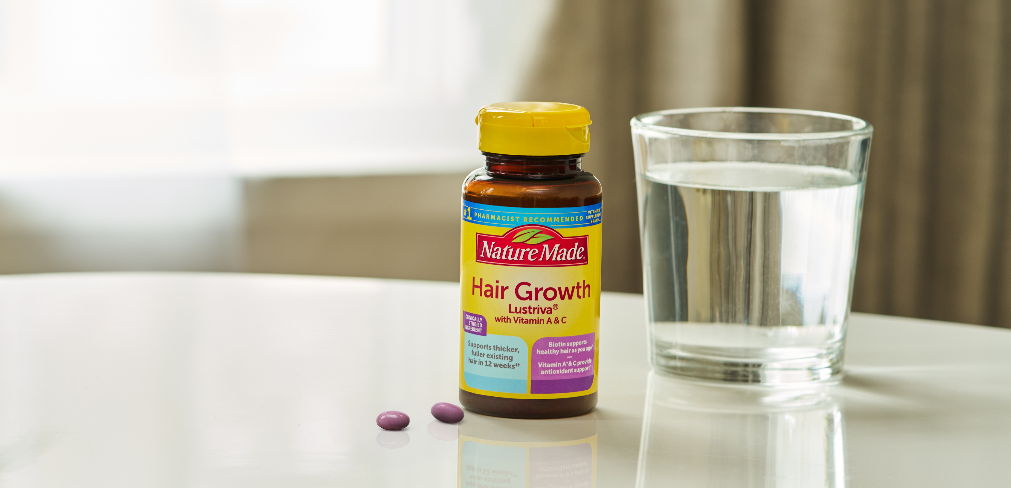 Hair Growth Lustriva® Softgels on counter with glass of water