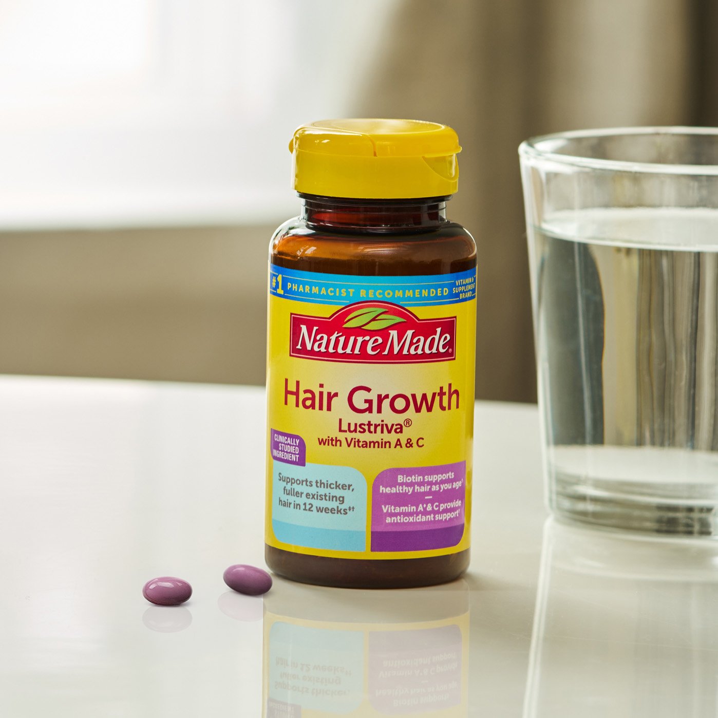 Hair Growth Lustriva® Softgels on counter with glass of water