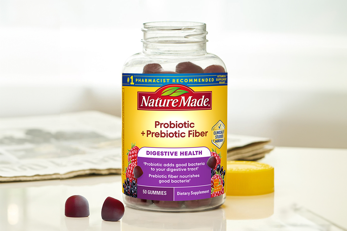 Probiotic + Prebiotic Fiber Gummies bottle with 2 gummies next to it on a table.