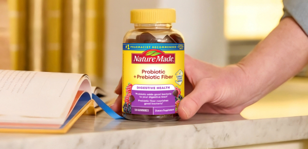 Hand reaching for a Probiotic + Prebiotic Fiber Gummies bottle on a counter.