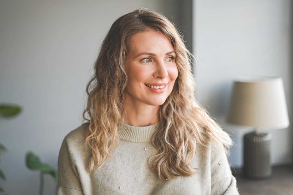 Person indoors looking toward a window in a bright room

