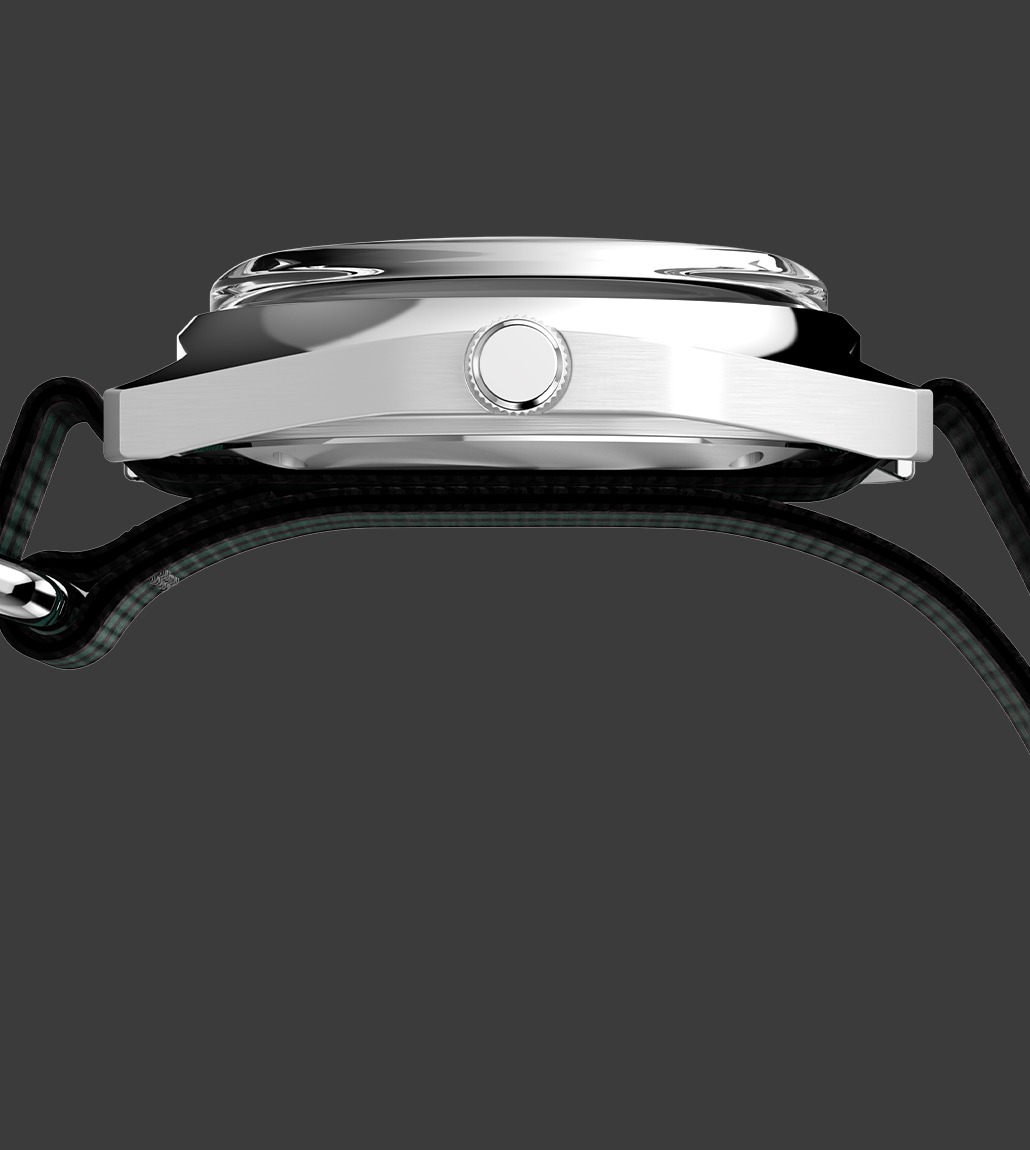 Side profile of the Q Timex® 1975 Enigma watch showing a brushed silver-tone case and domed crystal, paired with a NATO strap threaded through the watch lugs.