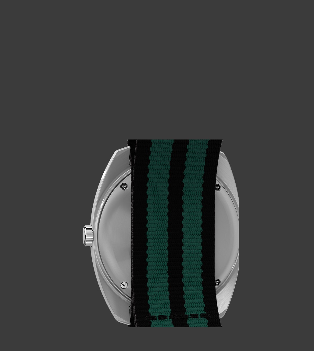 Rear view of the Q Timex® 1975 Enigma watch with its stainless steel case partially obscured by a black-and-green striped NATO strap, revealing screw-back construction and crown placement.