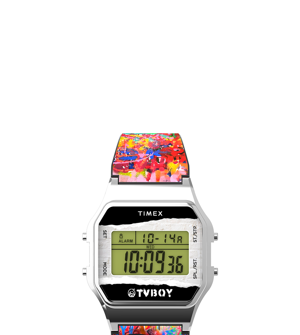 Front view of the Timex T80 x TVBOY digital watch with a colorful graffiti-inspired strap. The watch features a silver-tone rectangular case, digital display with date, time, and alarm indicators, and a white brick-texture backdrop on the face. The TVBOY logo is prominently displayed beneath the digital screen.
