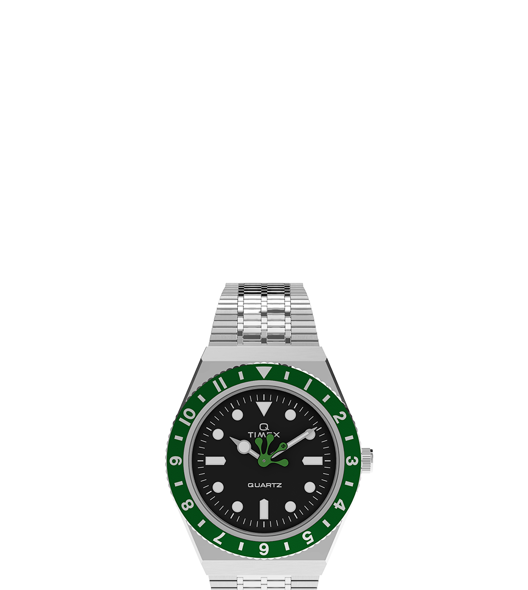 Front-facing view of the Timex x seconde/seconde/ collaboration watch featuring a stainless steel case and bracelet, black dial, and a bold green-and-black bezel. The watch face displays a playful green frog hand for the hour, with silver-tone hands for the minute and seconds, along with circular and rectangular hour markers and 'QUARTZ' printed on the dial.