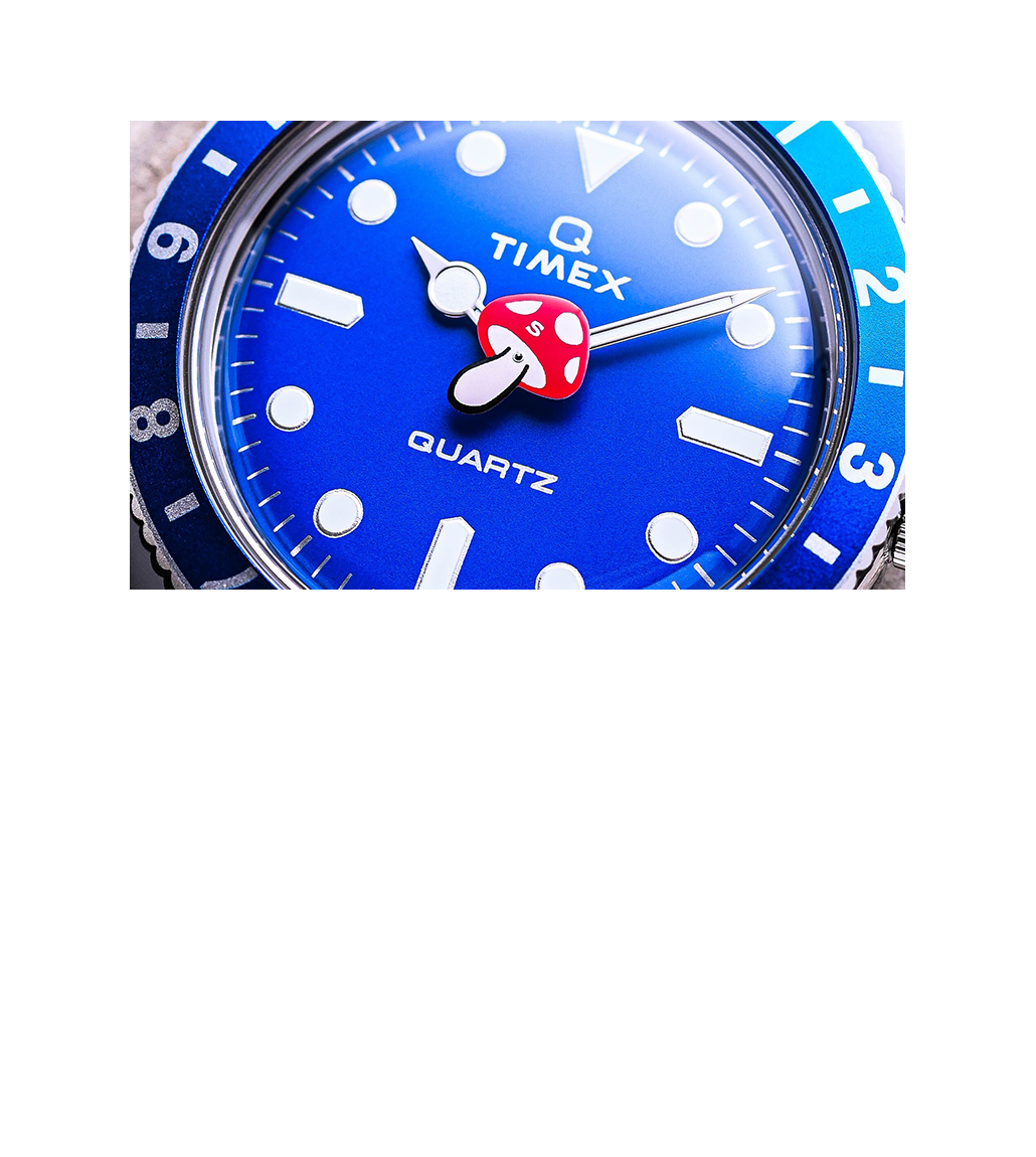 Close-up of the Timex x seconde/seconde/ Prequel Edition dial showing the vibrant blue face, bold indices, and quirky mushroom-shaped red hour hand. Silver-tone hands and a blue bezel with white numerals complete the fun aesthetic.