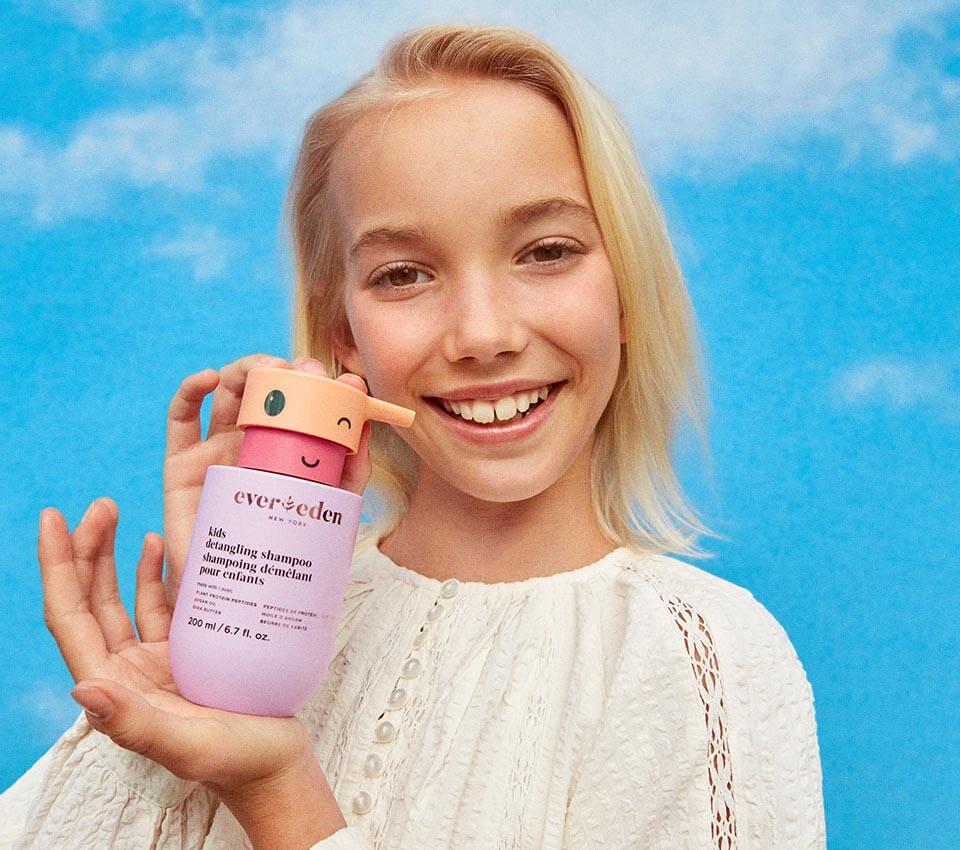 Girl holding Evereden skincare product and smiling.