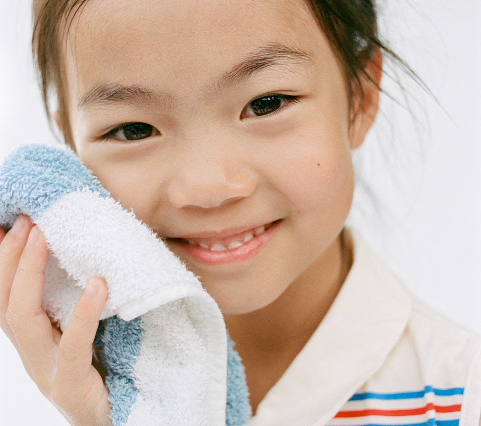 Child drying face with soft towel.