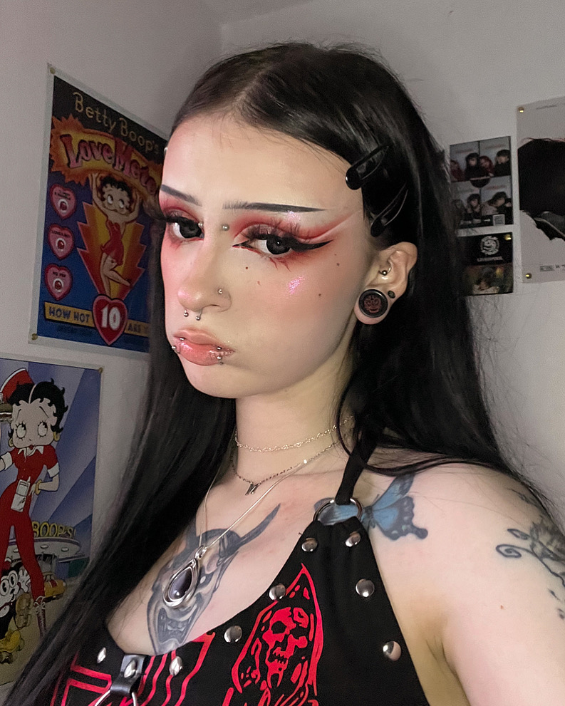 Woman wearing awesome demon face acrylic inlay and wood plugs / gauges