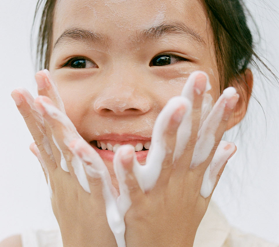 Smiling child washing face with foam