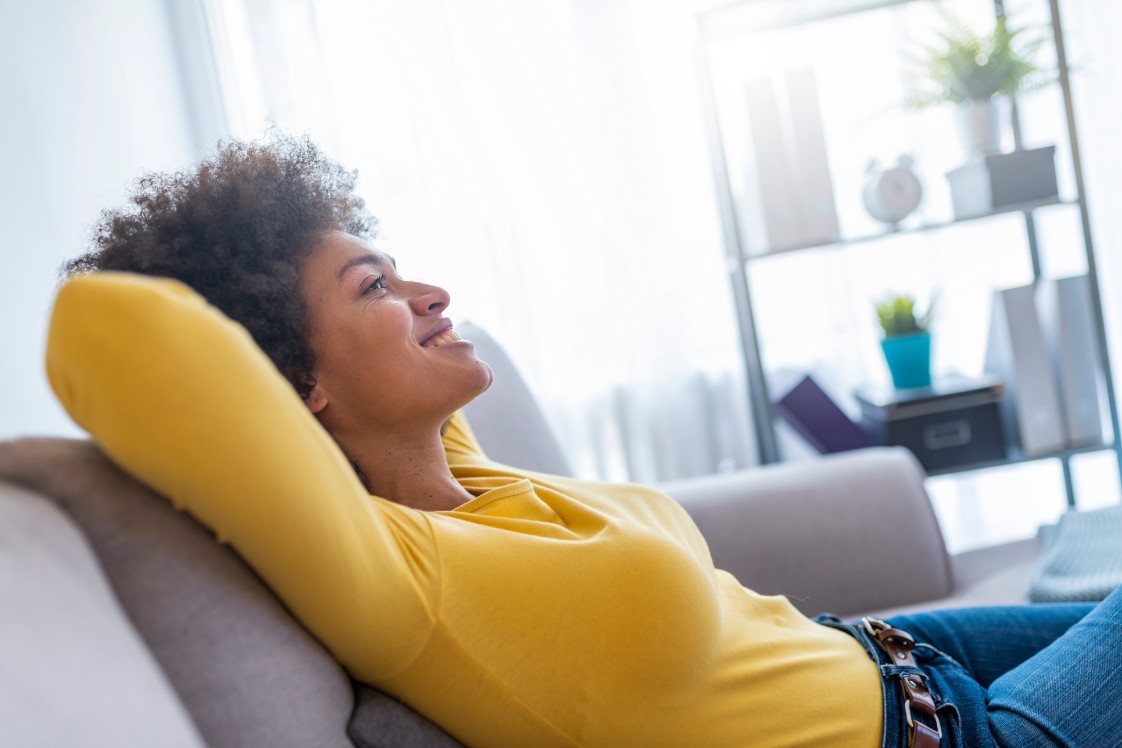 Woman in a yellow top leaning back, relaxed on a couch.
