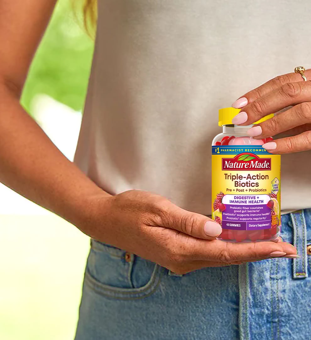 Person holding a bottle of Nature Made Triple-Action Biotic Gummies in front of their gut.