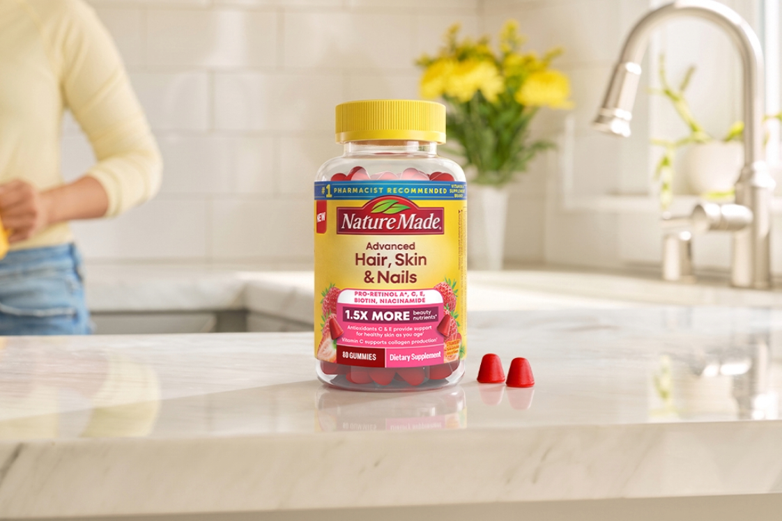 Nature Made Advanced Hair, Skin, Nails Gummies with two gummies on a kitchen counter.