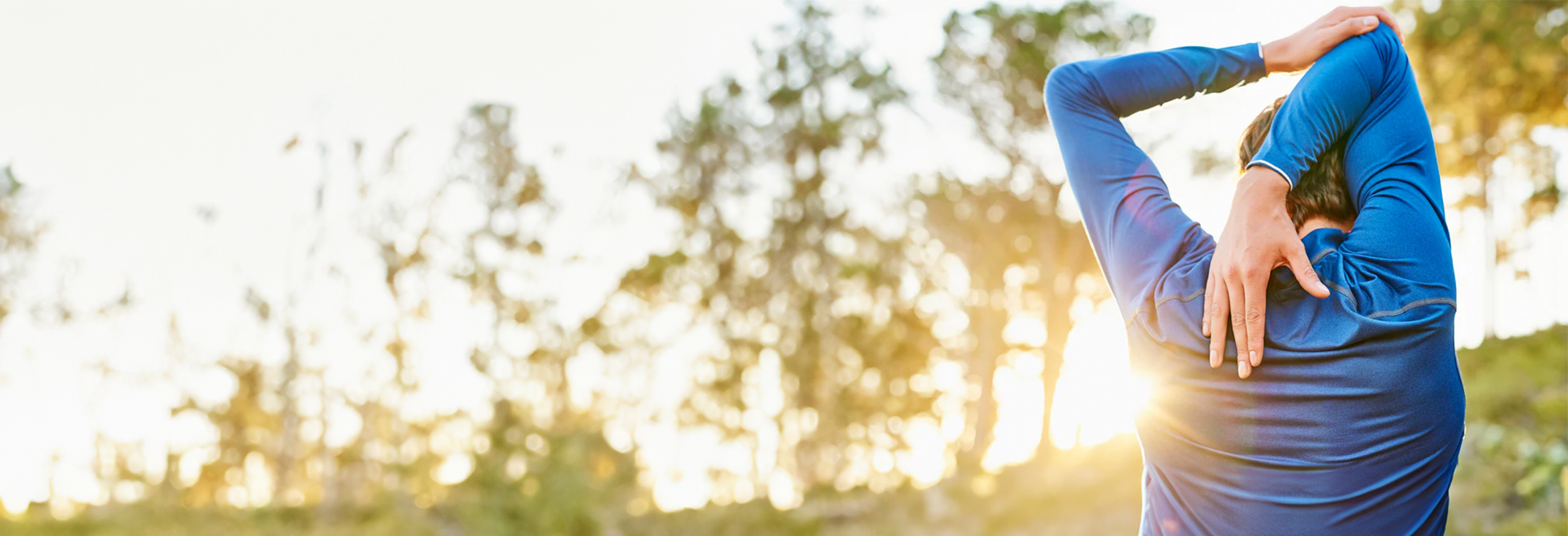 Person in blue workout top stretching outdoors.
