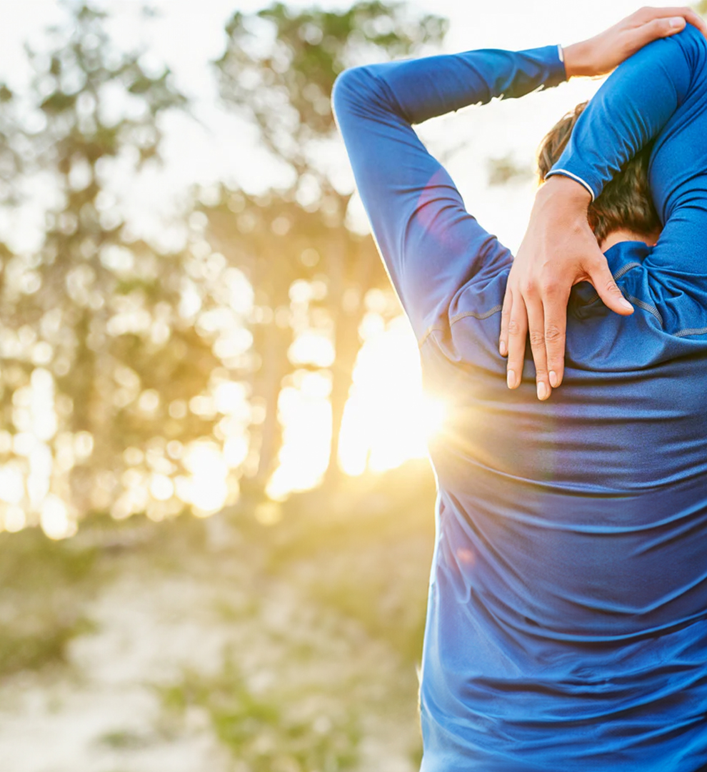 Person in blue workout top stretching outdoors.