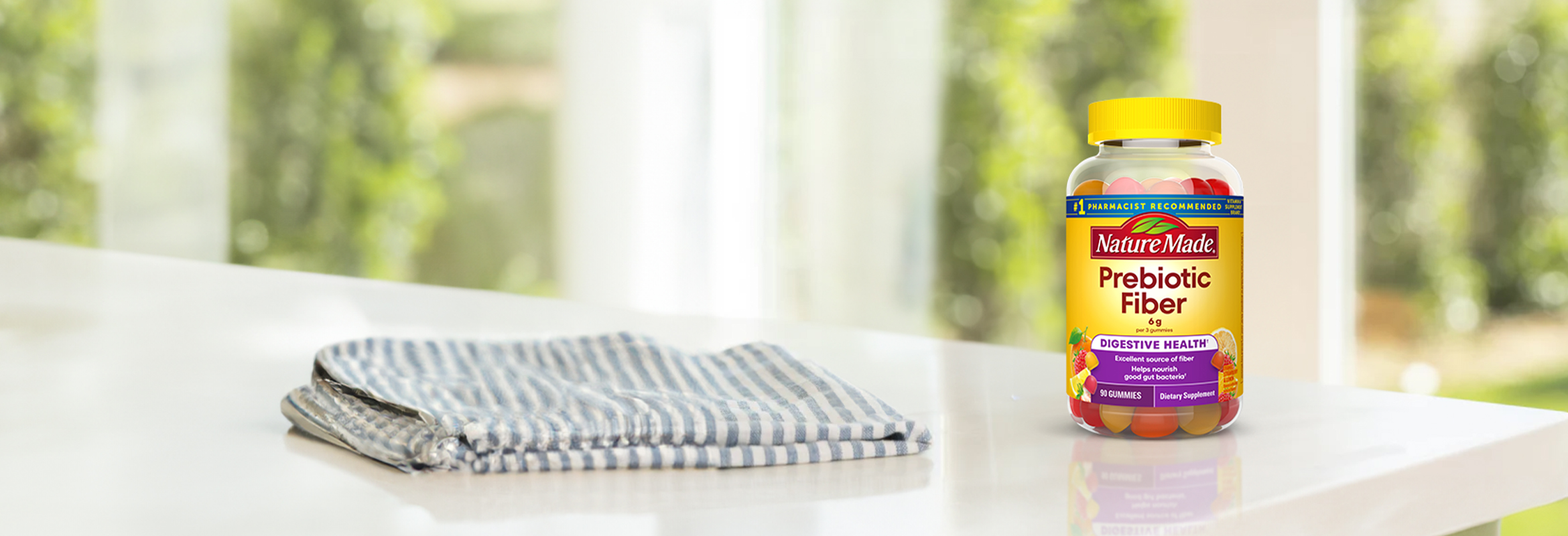 Nature Made Prebiotic Fiber gummies on a white counter next to a hand towel.