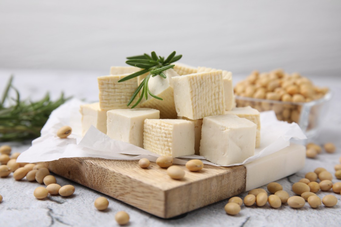 Probiotic food sources, cheese, soybeans on a chopping board.