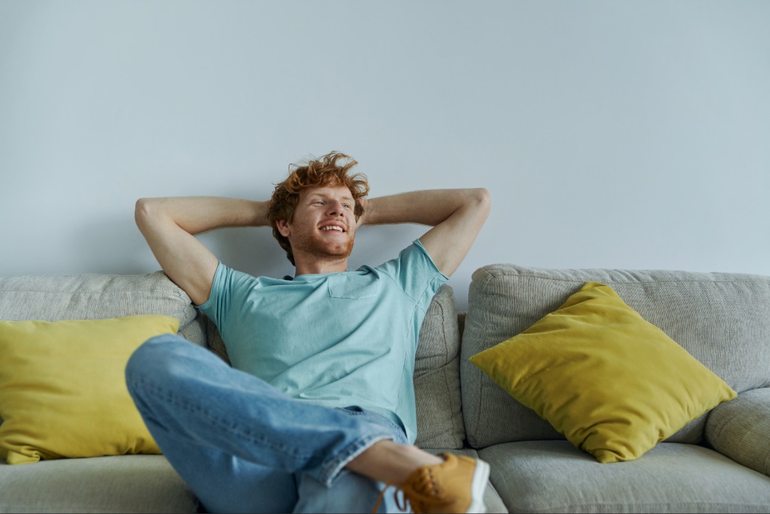 A person leaning back on a couch with throw pillows.