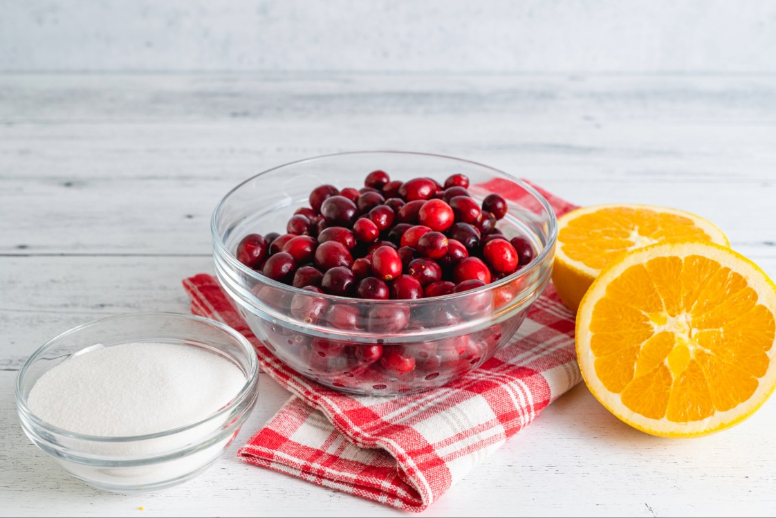 Cranberries and Oranges on a kitchen table.