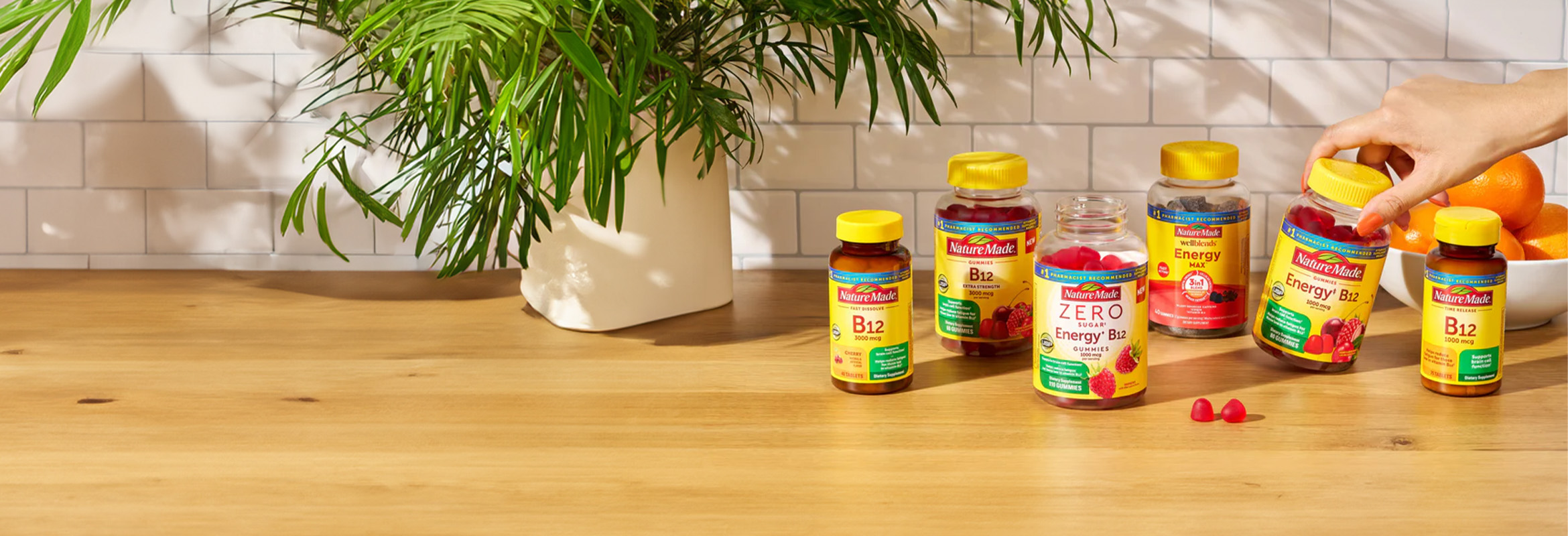 Nature Made B‑12 supplements on a wooden surface next to a plant.