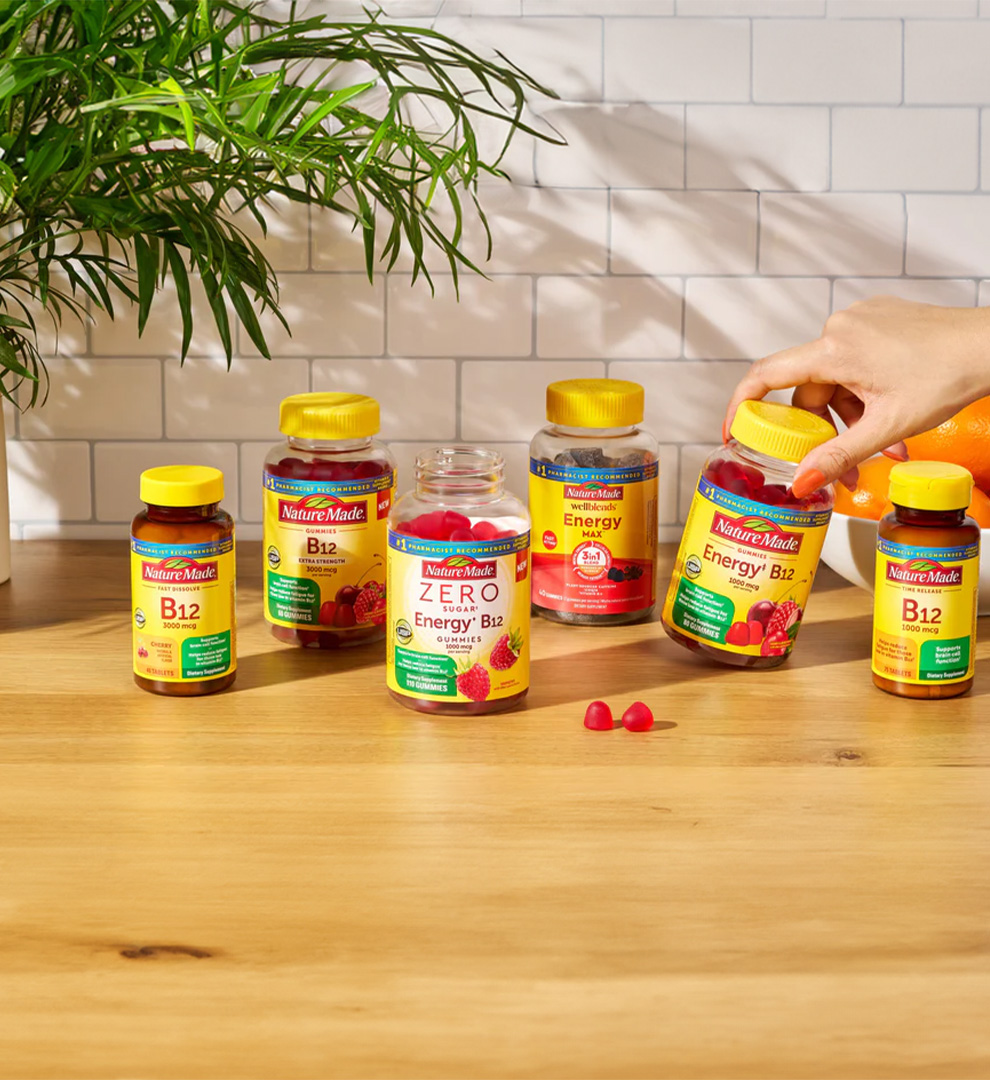 Nature Made B‑12 supplements on a wooden surface next to a plant.