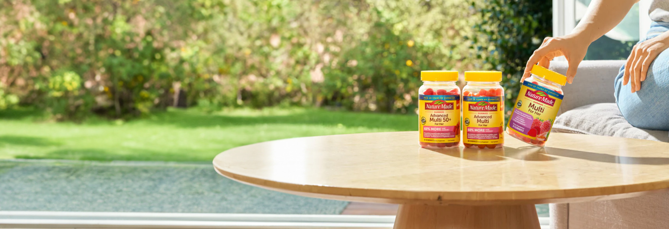 Nature Made multivitamin supplements arranged on a wooden table in a bright, sunlit home setting.